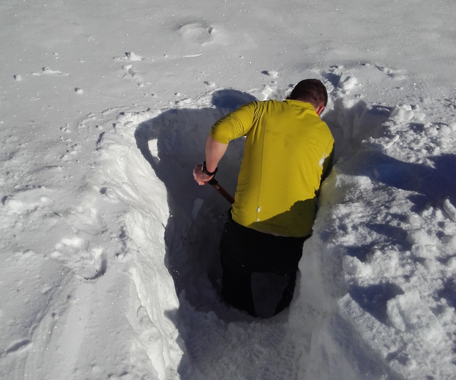 Ein Mann gräbt ein Loch in die Schneedecke, um das Schneehöhenradar zu platzieren.